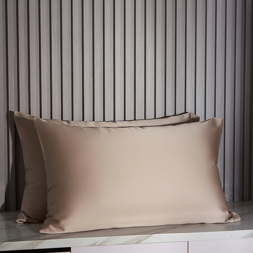 Khaki satin pillowcases on a marble surface with striped wall in the background