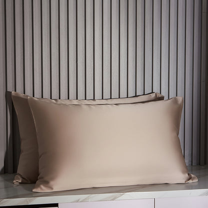 Khaki satin pillowcases on a marble surface with striped wall in the background