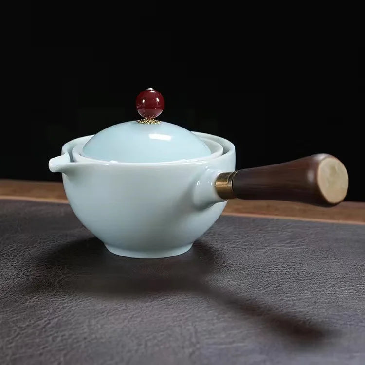 Tea pot with wooden handle on a dark surface