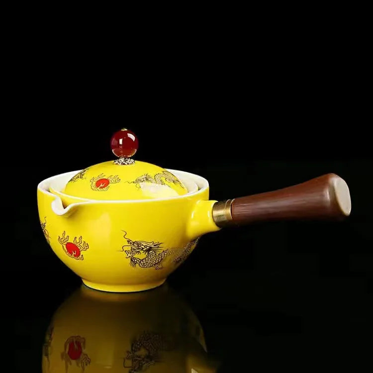 Yellow ceramic teapot with dragon design on a black background