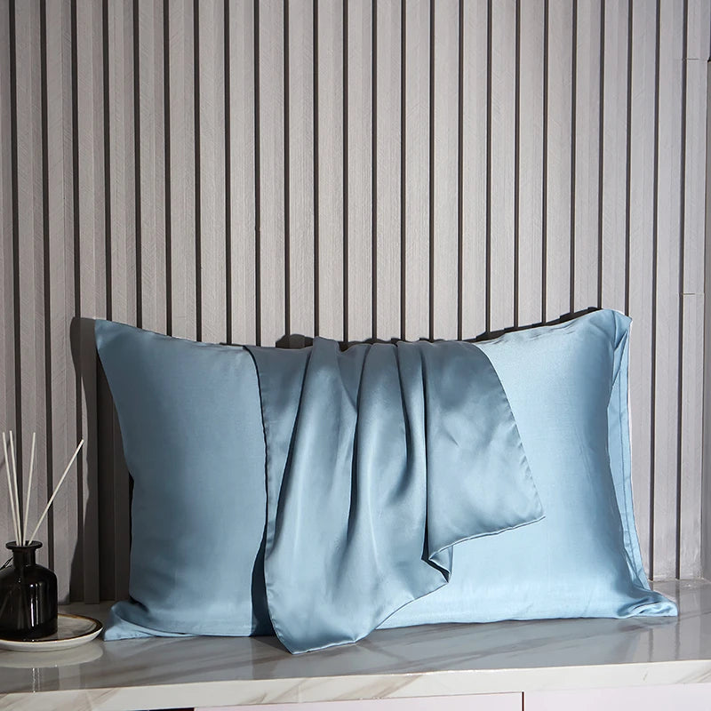 Blue satin pillowcases on a wooden surface with a striped wall background