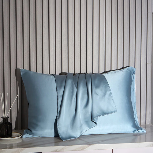 Blue satin pillowcases on a wooden surface with a striped wall background
