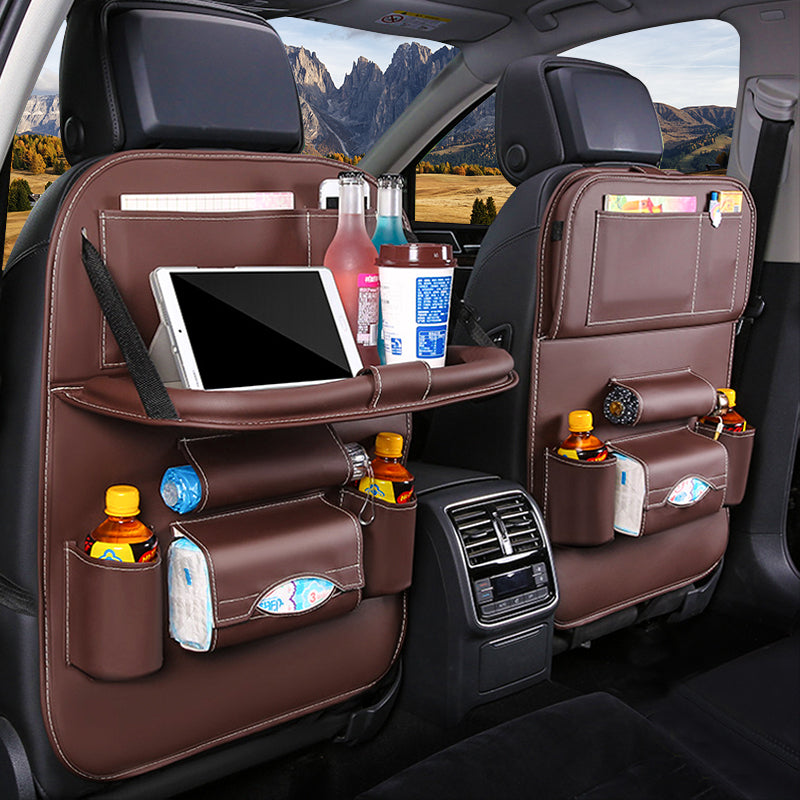 Car backseat organizer with multiple pockets holding a tablet, drinks, and snacks with a scenic view outside.