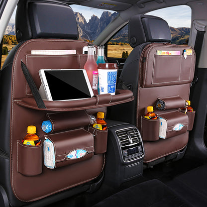 Car backseat organizer with multiple pockets holding a tablet, drinks, and snacks with a scenic view outside.