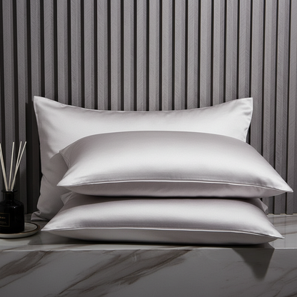 Three satin pillows on a marble surface with a striped wall in the background