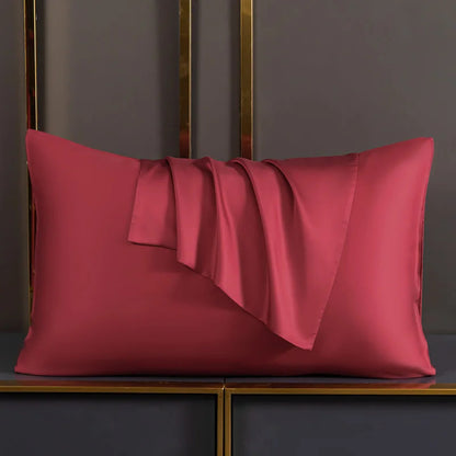 Wine Red satin pillow on a dark surface with a gold frame in the background