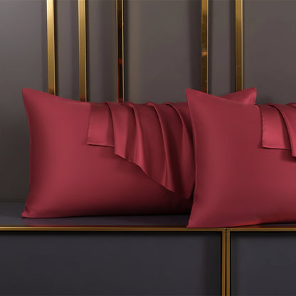 Wine Red satin pillow on a dark surface with a gold frame in the background