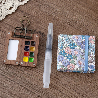 Wooden color swatch, clear plastic tool, and floral notebook on a wooden surface