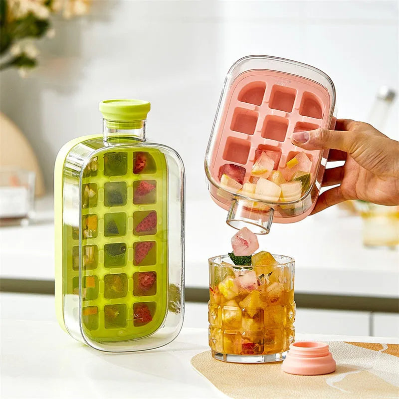 Two ice cube trays, one pink and one green, being used to add fruit ice cubes to a glass of juice.