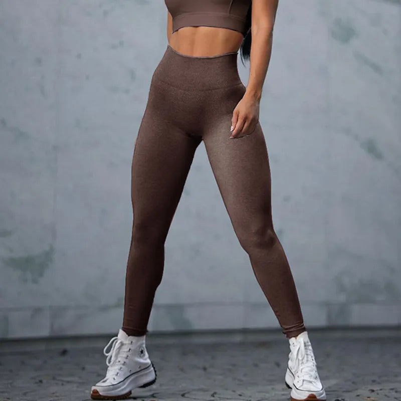 Person wearing brown athletic leggings and crop top against a gray background
