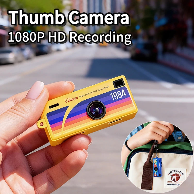 Small camera with '1984' design held in a hand, with street scene in the background