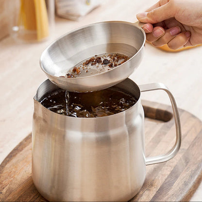 Stainless steel strainer being used to filter coffee into a mug on a wooden coaster.