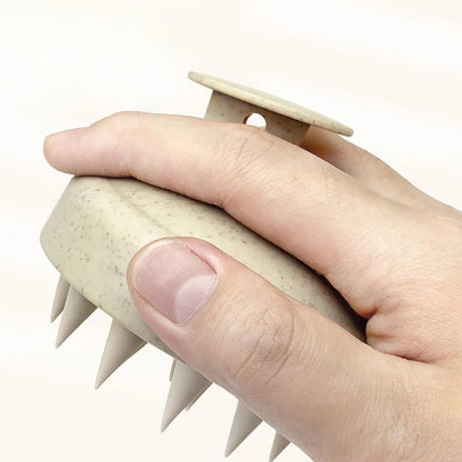 Hand holding a beige scalp massager with a white background