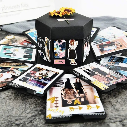 Black hexagonal photo album with cut-out decorative elements on a surface with scattered photos.