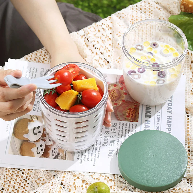 Person holding a container of fruit salad with a glass of milk on a newspaper surface.