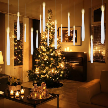 Decorative candles hanging from the ceiling in a living room with a Christmas tree.