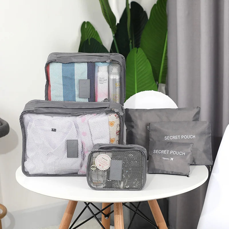Set of gray packing cubes with items on a white table against a neutral background