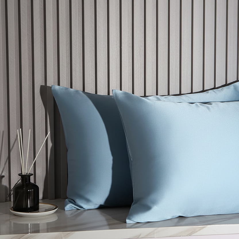 Two light blue pillows on a wooden surface with a striped wall in the background.
