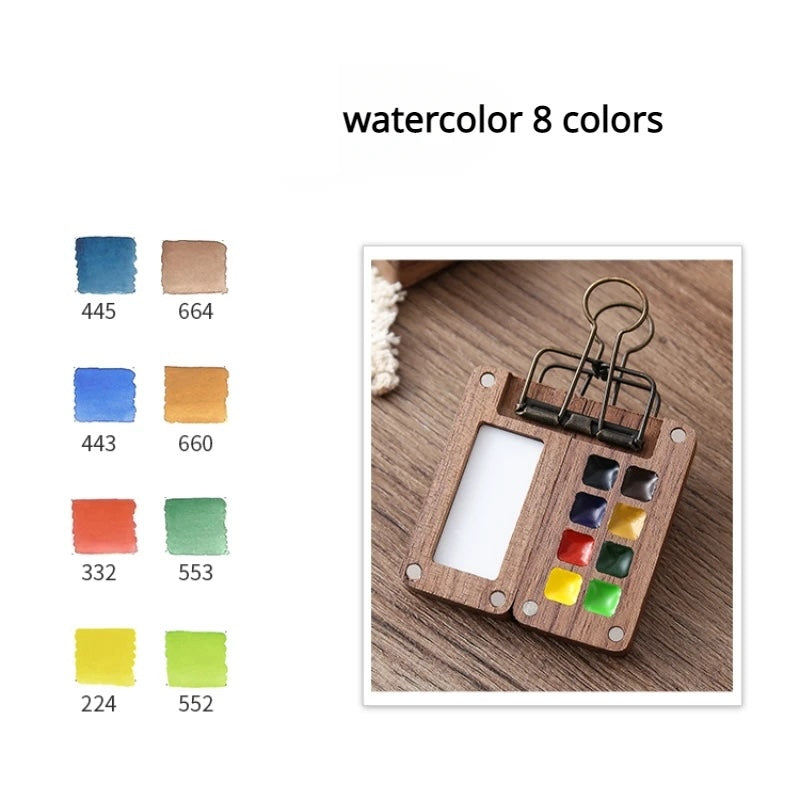 Wooden palette with watercolor swatches and a clip on a wooden surface.