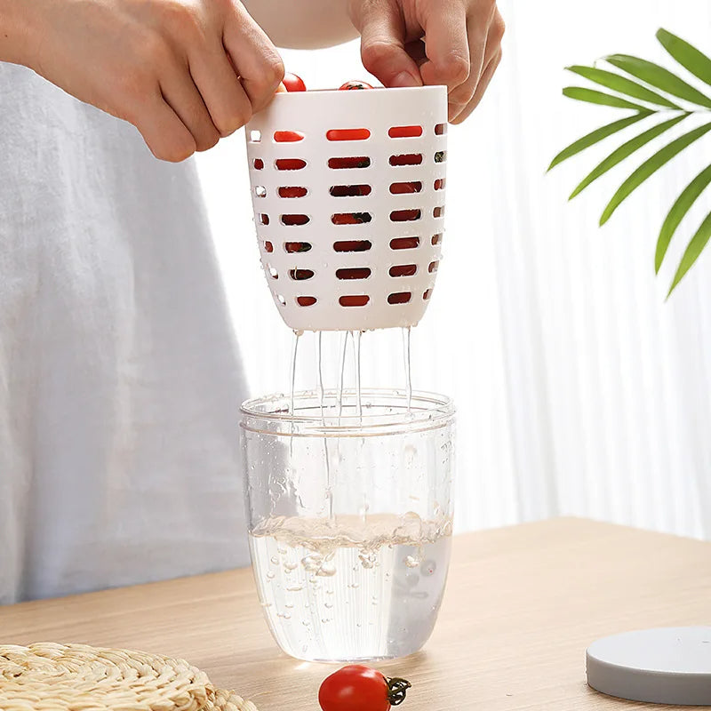 Person using a cherry pitter to remove pits from cherries over a glass of water on a wooden table.