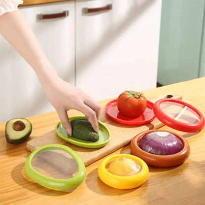 Colorful kitchen tools on a wooden surface with a hand reaching for an avocado.