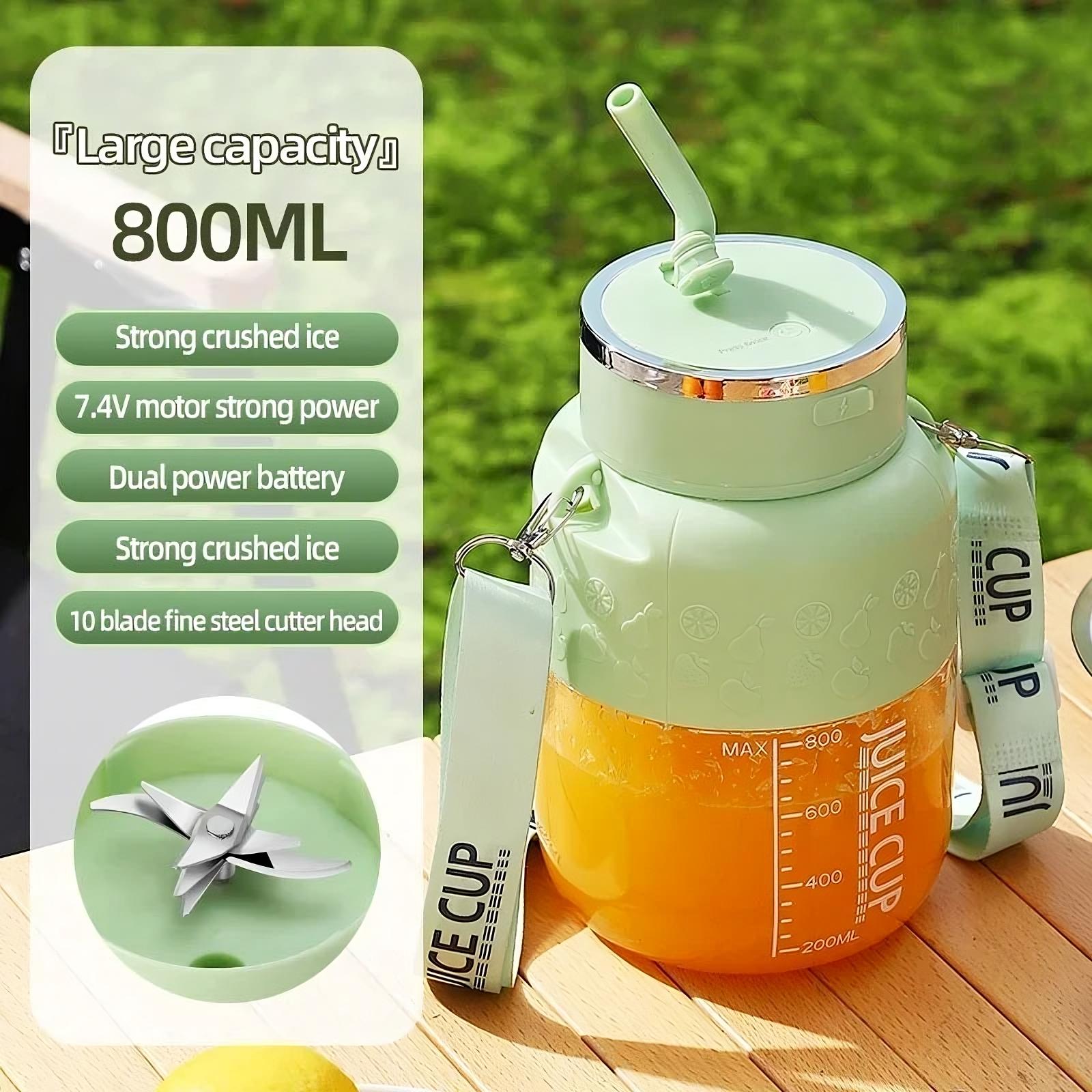 Green juice cup with straw, blade, and packaging on a wooden surface with greenery in the background