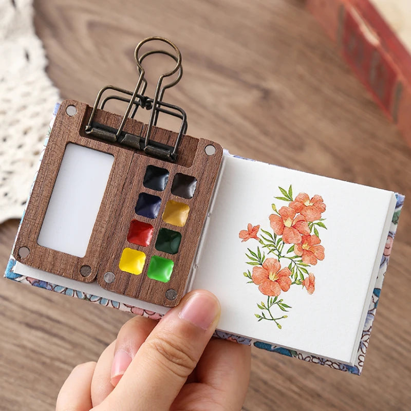 Small wooden art palette with watercolor flowers on a wooden surface