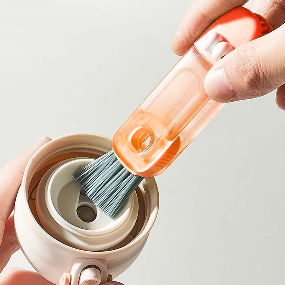 Person using a small brush with an orange handle to clean inside a white cup.