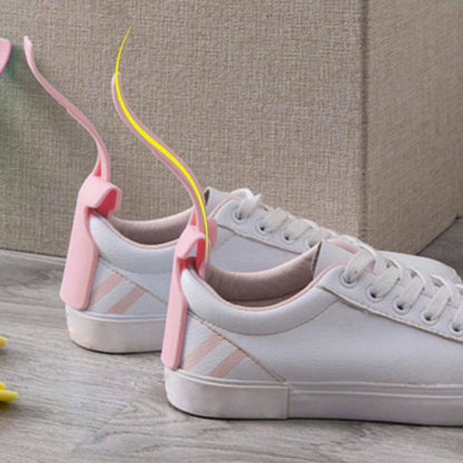 White sneakers with a pink shoe tree on a wooden floor.