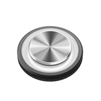Round metallic object with black base on a white background