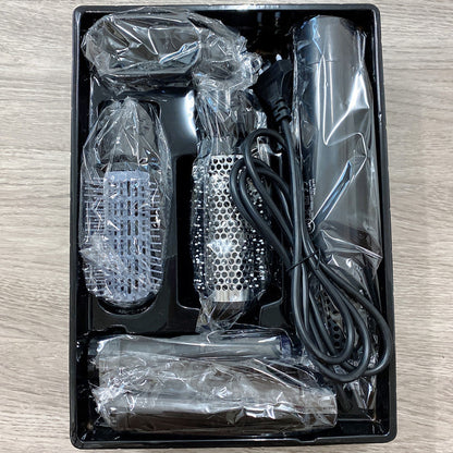 Grooming kit with hair dryer, brush, and attachments in a black box on a wooden surface.