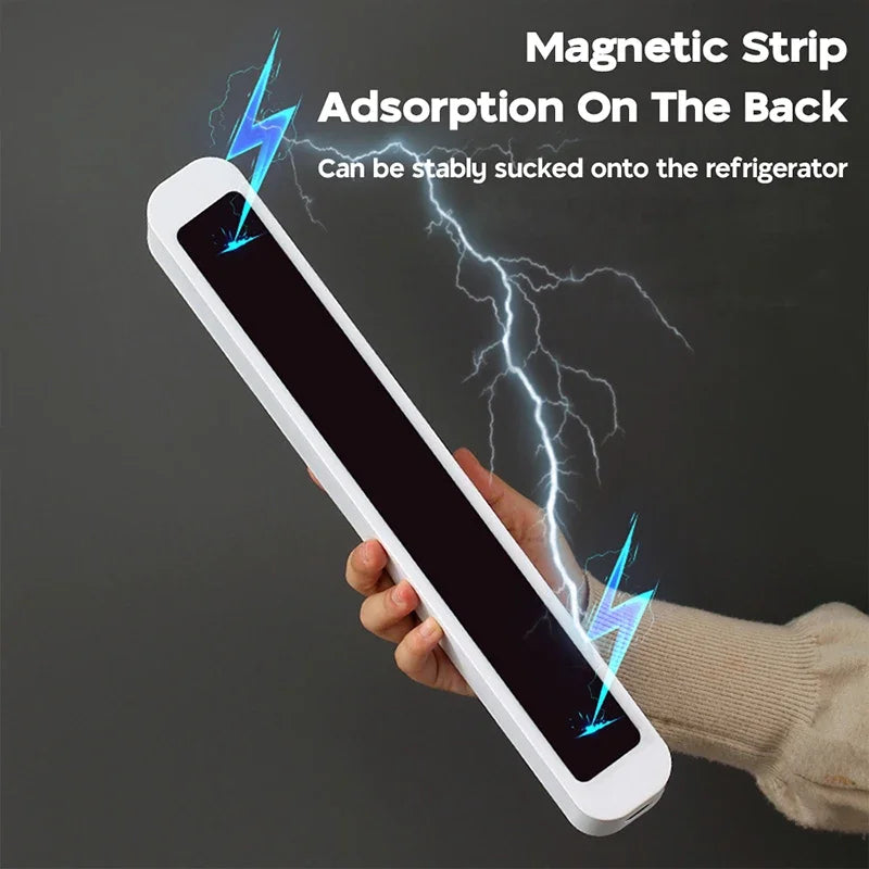 Hand holding a white electronic device with a magnetic strip吸附 on the back, against a dark background.