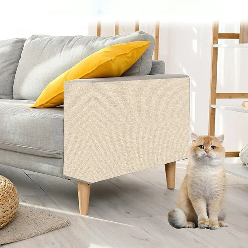 Cat sitting on a light wooden floor in a living room with a gray sofa and yellow pillow.