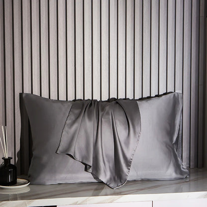 Dark Gray satin pillowcases on a marble surface with striped wallpaper in the background