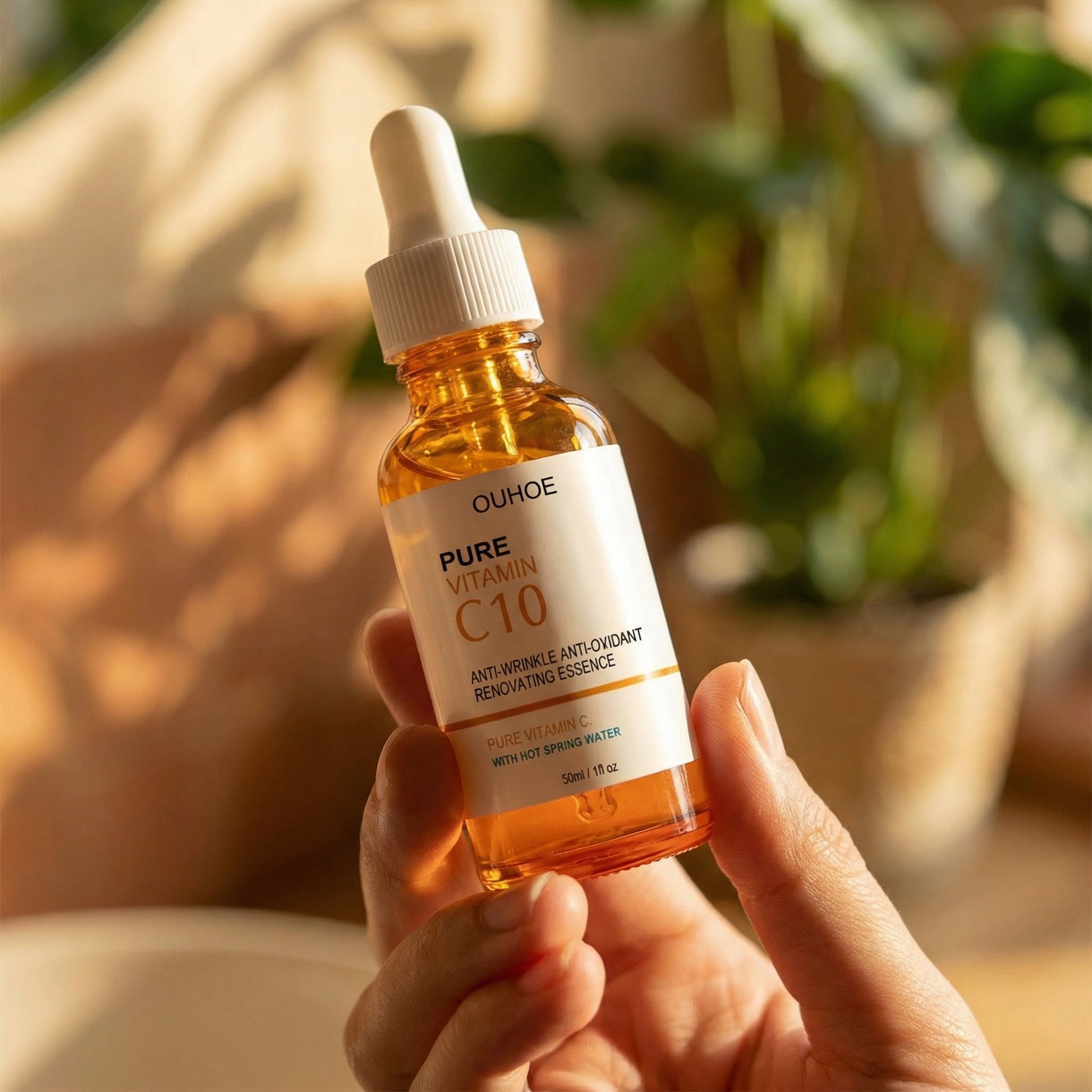 Hand holding a bottle of OUHOE Pure Vitamin C10 skincare serum with a blurred natural background.